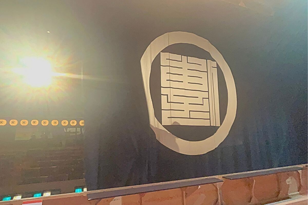 The curtain bearing the Awaji Ningyoza logo mark “傳Den” opens.